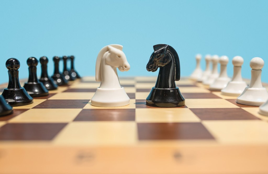 Two chess pieces on a board facing each other, symbolizing business competition. Understanding a company’s competitive position in the market can help you assess its strength and long-term stability. Researching competitors allows you to evaluate how the company stands in its industry and whether it’s the right fit for your career goals.