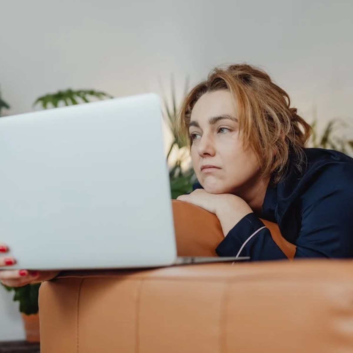 A woman staring sadly at her laptop screen, conveying feelings of frustration or self-doubt during her job search.