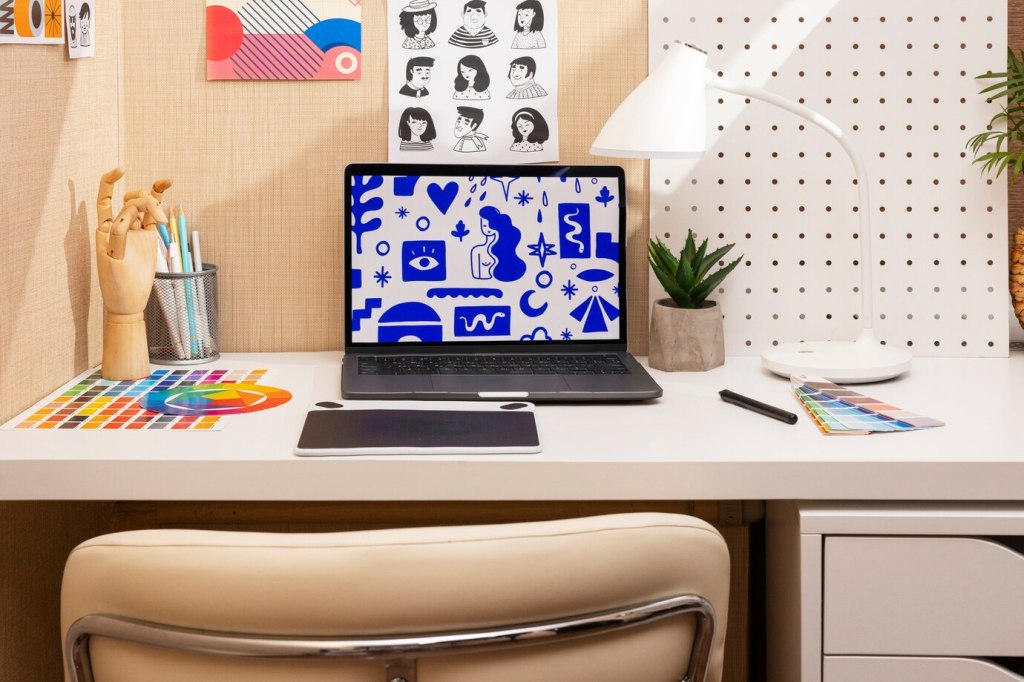 A computer desk with personal touches, including a plant, framed artwork, and decorative items, creating an inviting and stylish workspace.