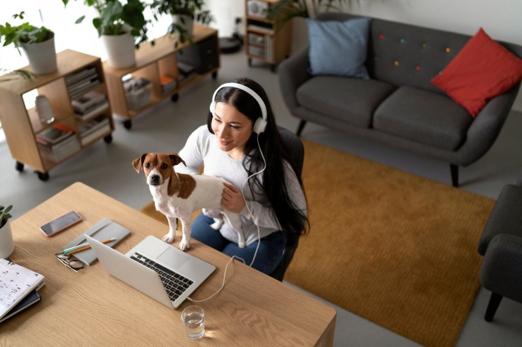 Remote worker balancing productivity and pet care with a dog on her lap in a cozy home office.