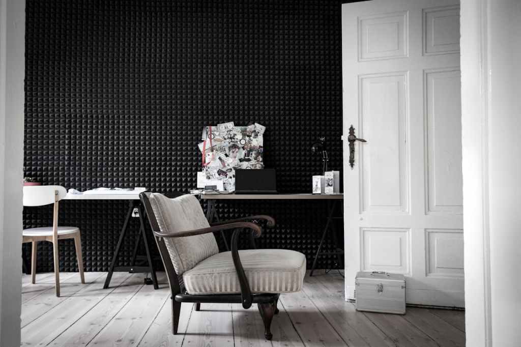 A minimalist home office corner featuring a wall covered in black acoustic foam panels, demonstrating the use of sound-absorbing material to improve room acoustics.