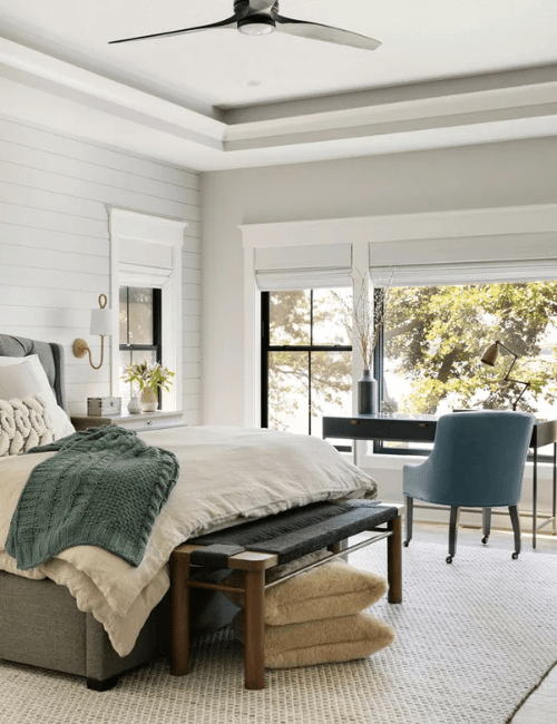 An elegant room featuring a teal accent chair, window views, and a designated office nook.