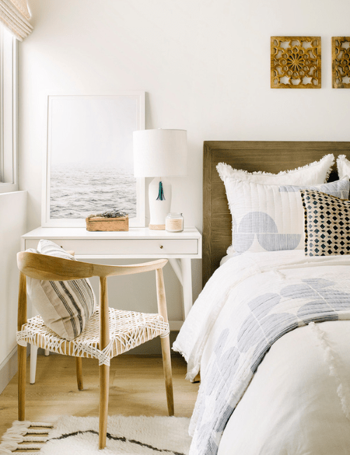 A light and airy room with white furniture, including a small  desk and comfortable chair perfect for a compact workspace in a bedroom.