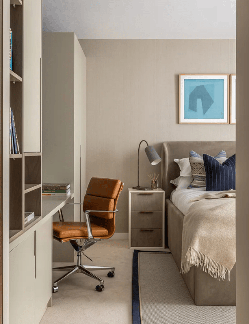 A simple, functional space with a dedicated office nook featuring a gray office chair and built-in desk area in a shared bedroom space.