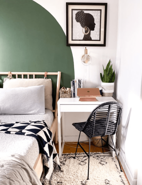 A contemporary space with a dark accent wall, black and white decor, and a sleek desk area positioned next to the bed.