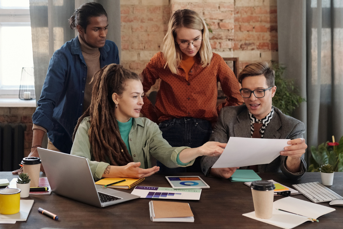 A group of coworkers collaborating in a meeting, with one overachiever proudly showcasing their work to the team.